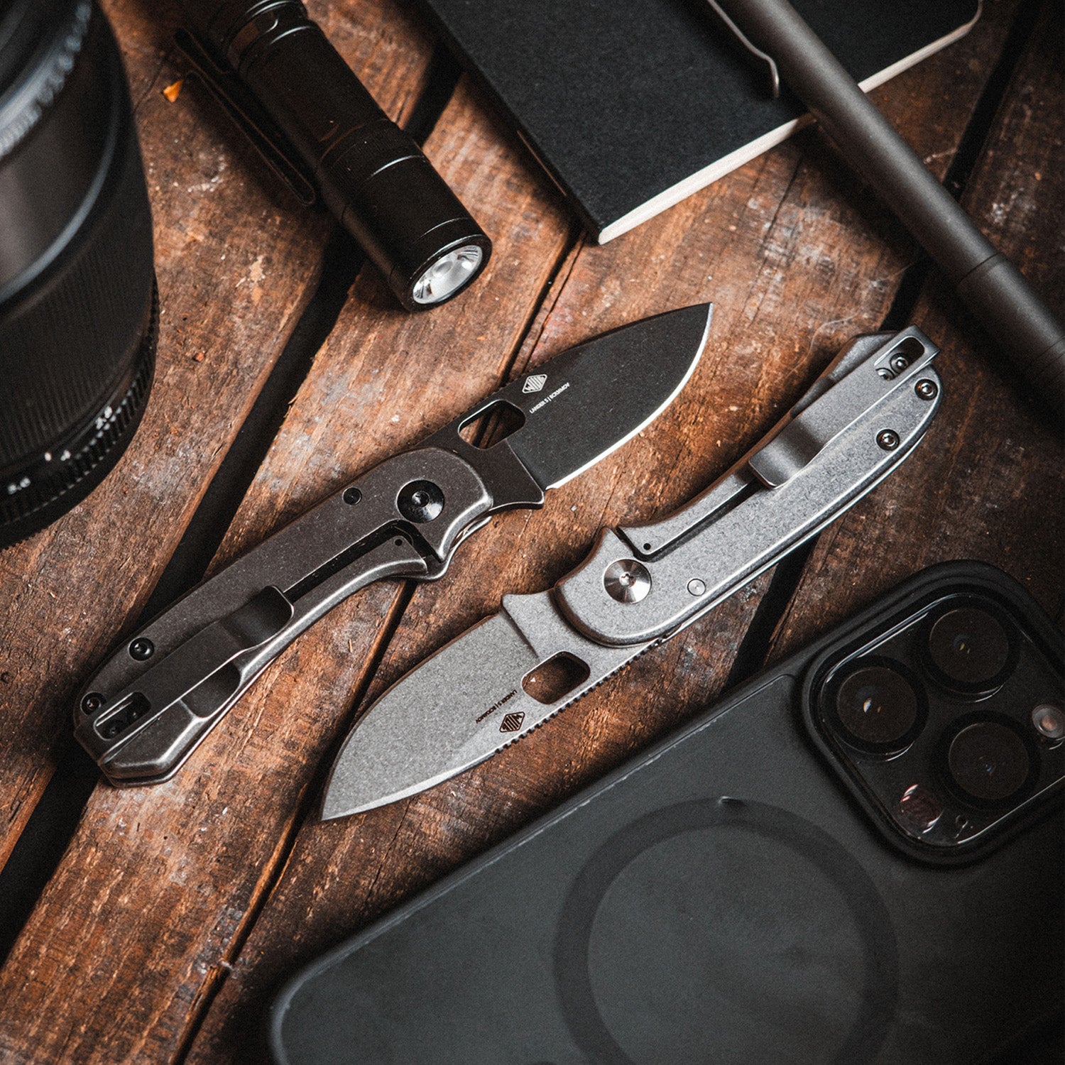 Lander 5 Black and Gray on a wooden surface with a flashlight, phone, and other items.