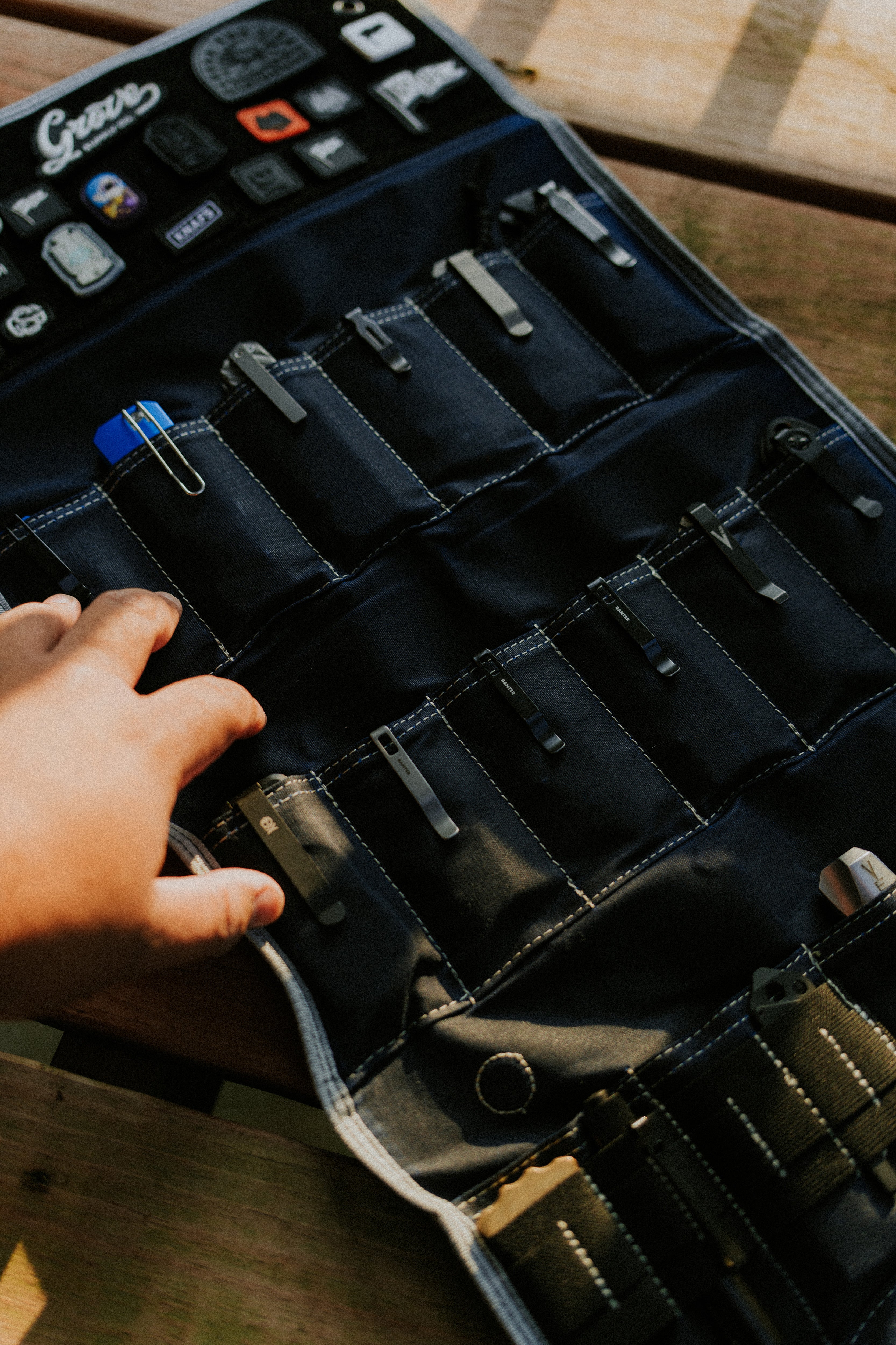 Hand holding open Burrito Grande Navy Blue Edition knife roll showing tools inside